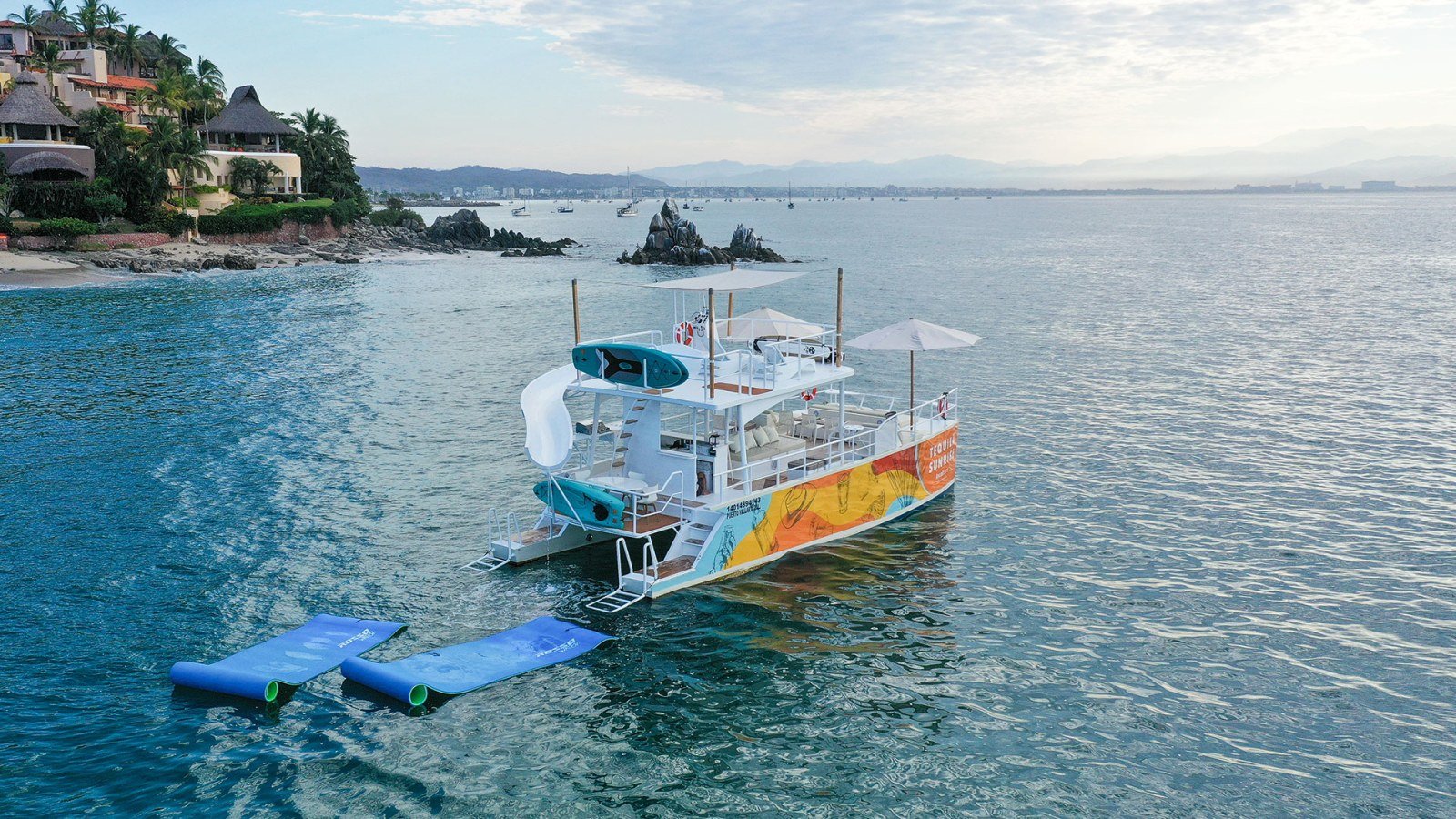 El catamarán de fiesta de 45 pies con tobogán fondeado cerca de Los Arcos durante una fiesta en yate en Puerto Vallarta