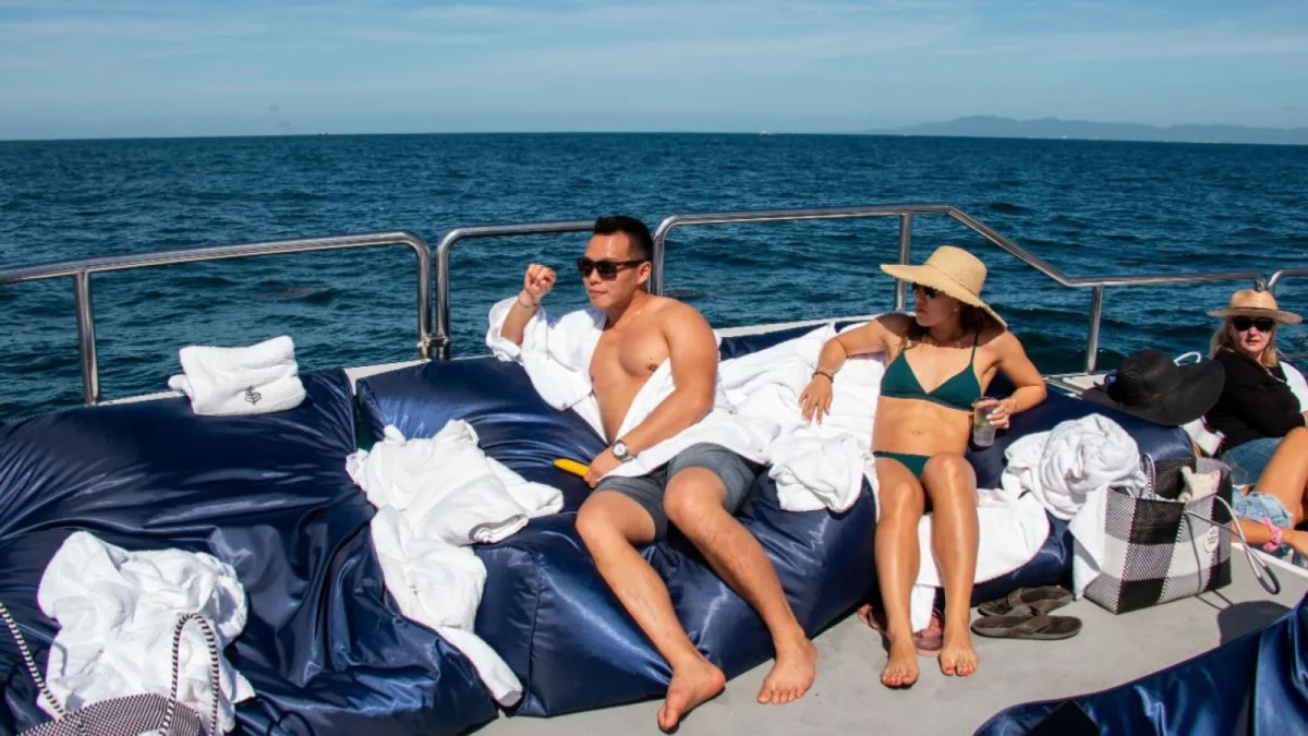 Invitados recostados en los camastros del catamarán de fiesta de 90 pies de Nuevo Vallarta